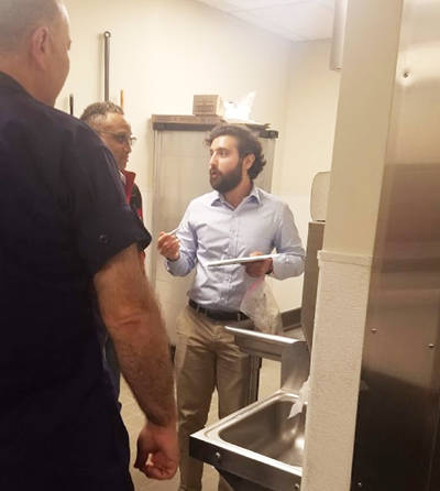 Adam Friedlander (FMI) discussing proper environmental monitoring techniques in a kitchen facility with regulatory officials.