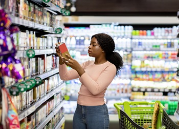 woman looking at product in grocery store aisle