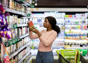 woman looking at product in grocery store aisle
