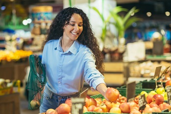 GLP1 Blog woman picking up apples at grocery store
