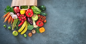 FreshForward Images with Grocery Bag bag of groceries with fresh fruits and vegetables coming out of it onto a countertop.