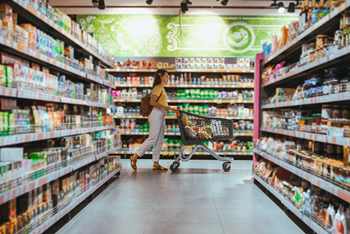 Woman walking down grocery aisle with cart