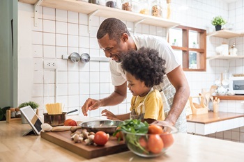 Father and kid making dinner from a recipe