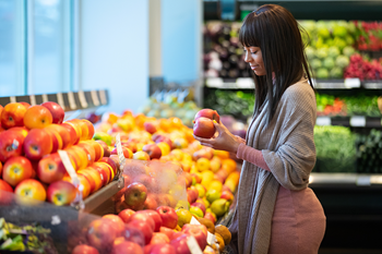 Woman looking at apples in grocery store