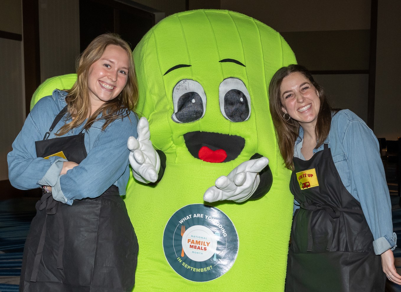 Two female posing with Family Meals green mascot